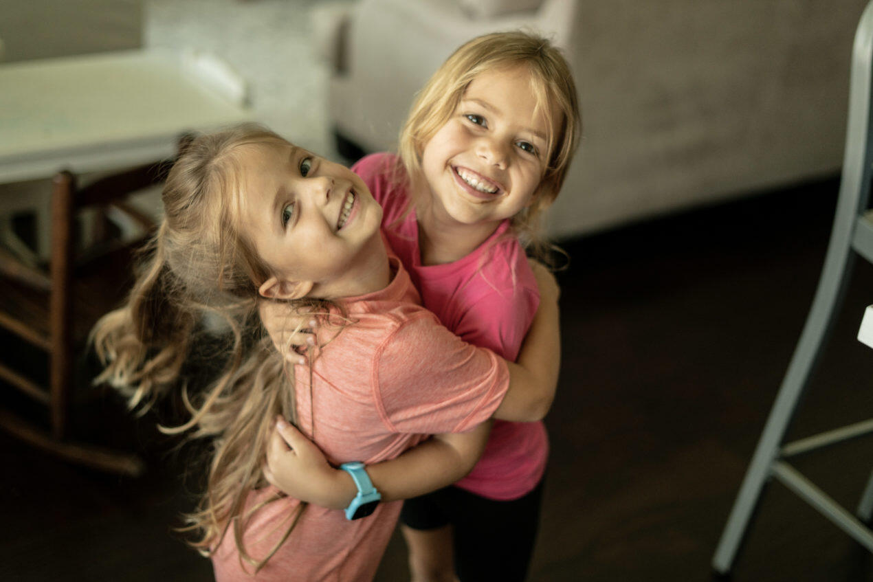 Twin girls hugging and grinning