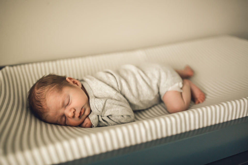 Newborn sleeping on changing pad atop blue dresser