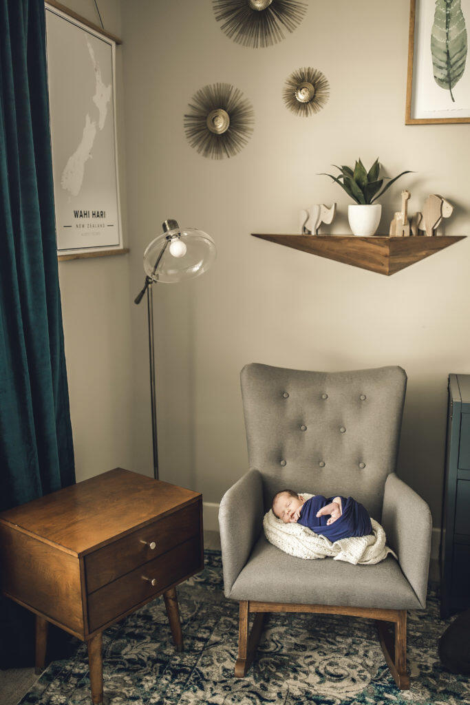 Newborn swaddled on nursery rocker in mid century modern nursery