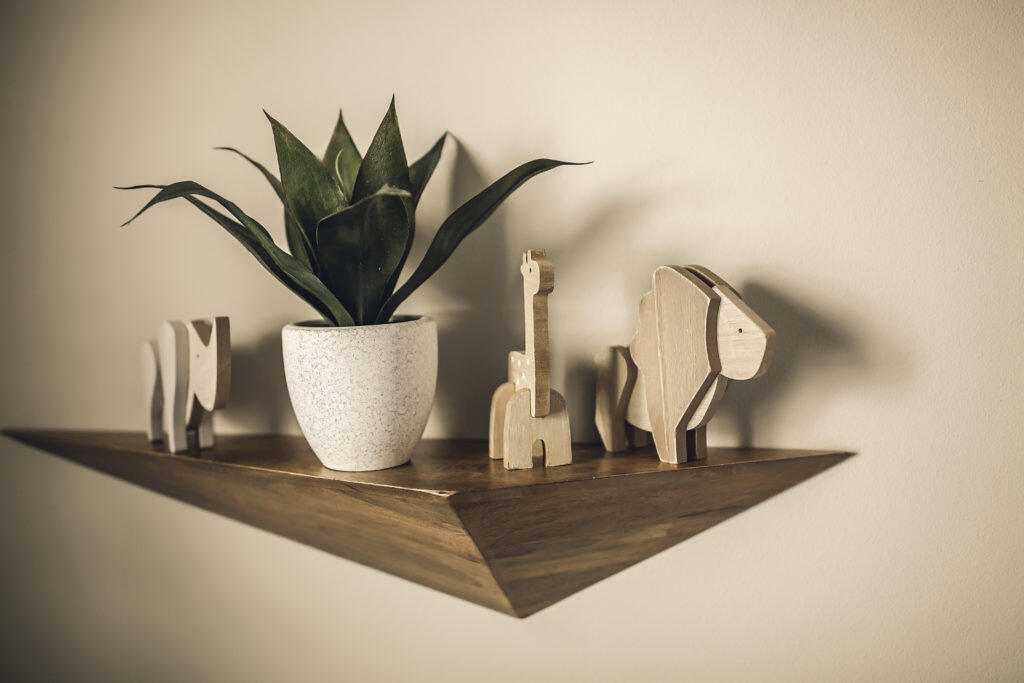 Prism shelf with faux foliage plant and wood animals
