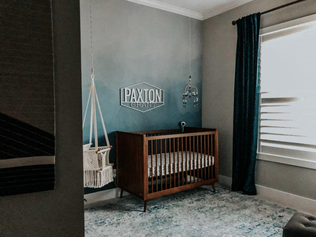 Mid century modern warm nursery with crib, swing, and floor to ceiling velvet curtains